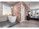 Elegant bathroom with freestanding tub, brick accent wall, and adjoining main bedroom at 15753 W Christy Dr, Surprise, AZ 85379