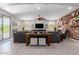 Open concept living room features a brick accent wall, a large sectional sofa, and a view of the backyard at 15753 W Christy Dr, Surprise, AZ 85379