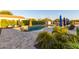 A private backyard oasis with a large pool, sun loungers, manicured landscaping, and a storage shed at 15753 W Christy Dr, Surprise, AZ 85379