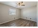 A gray-walled bedroom with a ceiling fan, window, and faux-wood flooring at 15845 N 60Th Dr, Glendale, AZ 85306