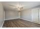 Spacious bedroom with a ceiling fan and light, hardwood flooring, base trim, and neutral grey colored walls at 15845 N 60Th Dr, Glendale, AZ 85306