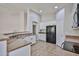 An open concept kitchen showcasing white cabinets, black appliances, granite counters, and tile flooring at 16874 W Tonbridge St, Surprise, AZ 85374
