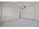 An empty living room featuring neutral carpet, a vaulted ceiling, and a modern ceiling fan at 16874 W Tonbridge St, Surprise, AZ 85374