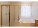 Bathroom showcasing a glass-enclosed shower and a soaking tub with a window at 170 E Canary Ct, San Tan Valley, AZ 85143