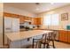 Well-lit eat-in kitchen with wood cabinets, stainless appliances, an island with bar seating, and tile flooring at 170 E Canary Ct, San Tan Valley, AZ 85143