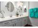 Bathroom featuring a dual sink vanity with white cabinets and round mirrors at 18650 N 91St Ave # 3301, Peoria, AZ 85382