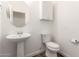 Stylish half bathroom with a pedestal sink, framed round mirror, and modern fixtures at 18675 W Foothill Dr, Surprise, AZ 85387