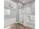 Modern bathroom with a glass shower and bathtub combination adjacent to a carpeted bedroom at 18675 W Foothill Dr, Surprise, AZ 85387