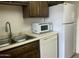 This kitchen offers white appliances, dark cabinets, a stainless steel sink, and neutral countertops at 1927 E Hampton Ave # 260, Mesa, AZ 85204
