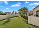 Spacious backyard with artificial turf, mature landscaping, palm trees, and a white privacy wall at 1940 E Citation Ln, Tempe, AZ 85284
