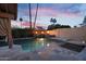 Inviting pool featuring fire bowls and flowing water, surrounded by stone tile under a pink and purple sunset sky at 1940 E Citation Ln, Tempe, AZ 85284