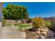 Landscaped backyard with grassy area, mature trees, and a decorative rock garden feature at 19851 N 35Th St, Phoenix, AZ 85050