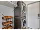 A functional laundry room with stacked washer and dryer and storage shelves at 19851 N 35Th St, Phoenix, AZ 85050
