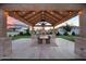 Inviting covered outdoor dining area with a built-in grill, stone pizza oven, and elegant lighting at 20649 E Vallejo Ct, Queen Creek, AZ 85142