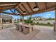 Inviting outdoor dining area featuring a large table, wicker chairs, and stylish lighting under a timber pavilion at 20649 E Vallejo Ct, Queen Creek, AZ 85142