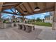 Outdoor kitchen featuring a built-in grill, pizza oven, and dining table under a timber pavilion at 20649 E Vallejo Ct, Queen Creek, AZ 85142