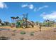Community playground with slides, climbing structures, and swings set against a bright blue sky at 22699 E Happy Rd, Queen Creek, AZ 85142