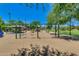 Community playground featuring swings, picnic tables, and mature shade trees on a sunny day at 2341 S Gordon --, Mesa, AZ 85209