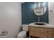 Stylish half-bathroom featuring dark blue wood paneling, a round mirror, and a vessel sink on a light wood vanity at 26286 N 45Th Pl, Phoenix, AZ 85050