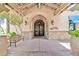 Inviting entrance to the Indigo Grille with arched doorway, stone accents, flowering plants, and decorative lights at 27606 W Tonopah Dr, Buckeye, AZ 85396