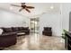 This open-concept living room features tile flooring, a ceiling fan, and a sliding glass door to the patio at 29751 N 119Th Ln, Peoria, AZ 85383