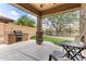 Covered patio area with built-in grill, artificial grass, and outdoor seating at 29751 N 119Th Ln, Peoria, AZ 85383
