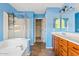 Blue bathroom featuring a walk-in shower, vanity with sink, and a soaking tub at 3623 E Horace Dr, Gilbert, AZ 85296