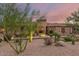 Elegant home exterior with desert landscaping, stone accents, and a grand entrance framed by lush greenery at 37301 N 99Th St, Scottsdale, AZ 85262
