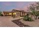 Charming home with stone accents, warm lighting, and a paved driveway surrounded by desert landscaping at 37301 N 99Th St, Scottsdale, AZ 85262