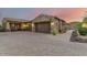 Home exterior featuring stone accents, a paved driveway, and well-manicured desert landscaping with sunset sky at 37301 N 99Th St, Scottsdale, AZ 85262
