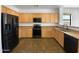 Well-equipped kitchen featuring dark appliances, wooden cabinets, and ample counter space at 43530 W Eddie Way, Maricopa, AZ 85138