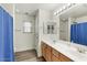 Bright bathroom features dual sinks, wood-look flooring, and a shower/tub combination with blue curtains at 462 W Myrtle Dr, Chandler, AZ 85248