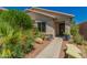 Charming desert home entrance featuring lush green landscaping and a cozy bench at 6031 N Milano Ct, Litchfield Park, AZ 85340