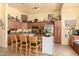 Eat-in kitchen featuring wood cabinets, stainless appliances, and a brick-accented island with bar stool seating at 6031 N Milano Ct, Litchfield Park, AZ 85340