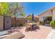Backyard patio featuring a dining table with seating, BBQ, storage and lush green landscaping at 6031 N Milano Ct, Litchfield Park, AZ 85340