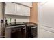 Well-lit laundry room with washer, dryer and white overhead cabinets provides ample storage at 634 W Aviary Way, Gilbert, AZ 85233