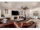 Living room featuring exposed aggregate floor, with modern ceiling fan, fireplace and a leather furniture set at 634 W Aviary Way, Gilbert, AZ 85233