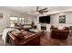 Living room featuring exposed aggregate floor, with modern ceiling fan, fireplace and a leather furniture set at 634 W Aviary Way, Gilbert, AZ 85233