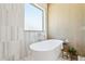 Modern bathroom with soaking tub, tiled walls, and a large window for natural light at 7032 E Balancing Rock Rd, Scottsdale, AZ 85266