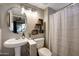 Bathroom featuring pedestal sink, round mirror and decorative floating shelves at 7857 N 21St Ave, Phoenix, AZ 85021