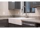 Close up of a modern kitchen with a farmhouse sink, gray cabinets, granite countertops, and stainless steel faucet at 7857 N 21St Ave, Phoenix, AZ 85021