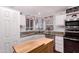 Bright kitchen featuring white cabinetry, stainless steel appliances, and a movable wooden island with butcher block at 8209 E 5Th Ave, Mesa, AZ 85208