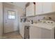 Practical laundry room with modern washer and dryer, overhead storage, and access to the backyard at 9157 W Gary Rd, Peoria, AZ 85345