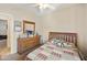 Well-lit bedroom with a decorative quilt, wooden dresser, and a ceiling fan at 992 S Roanoke St, Gilbert, AZ 85296