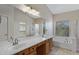 Bright bathroom features a double sink vanity, soaking tub, and glass-enclosed shower in this home at 10758 E Lobo Ave, Mesa, AZ 85209