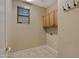 Functional laundry room offering upper cabinets, tile flooring, and ample space for appliances at 10758 E Lobo Ave, Mesa, AZ 85209