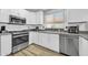 Modern kitchen featuring stainless steel appliances, white cabinets, a tiled backsplash, and wood-style flooring at 13233 W Mauna Loa Ln, Surprise, AZ 85379