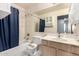 This bathroom has a tub and shower combo with a blue curtain, and a wooden vanity at 1433 E Mineral Rd, Gilbert, AZ 85234