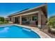 Covered patio with an outdoor dining set, grill, landscaped yard and a swimming pool with a tanning shelf at 14571 W Wethersfield Rd, Surprise, AZ 85379