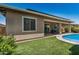 An outdoor living space with a covered patio and outdoor seating next to the pool with artificial turf at 14571 W Wethersfield Rd, Surprise, AZ 85379